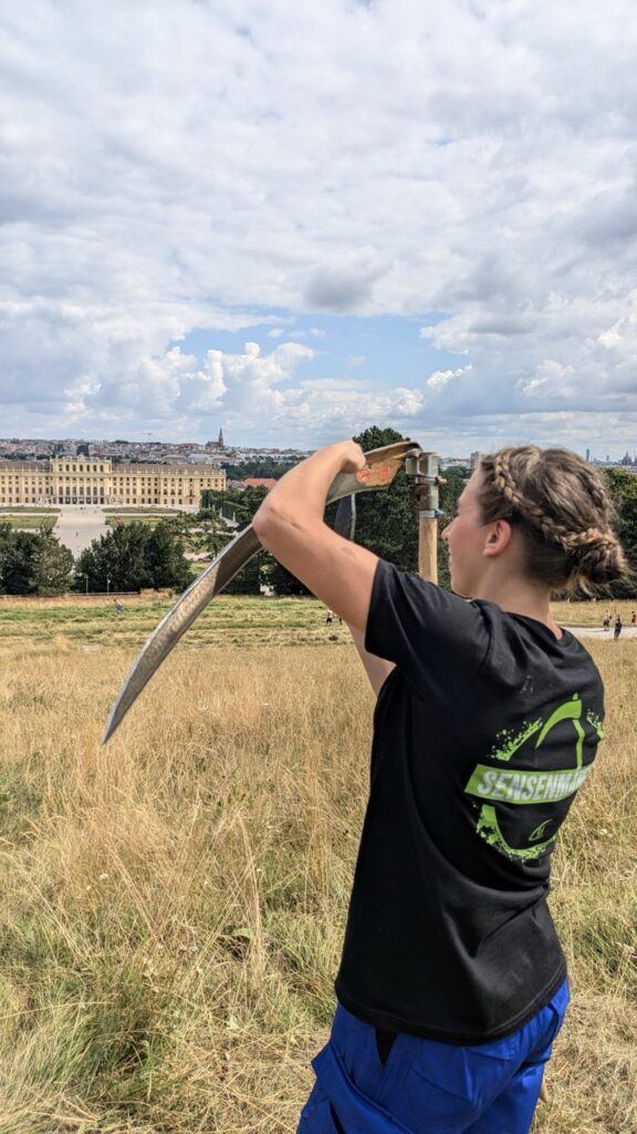 Teilnehmerin am Sensemähevent der Landjugend Österreich mit einer Sense in der Hand