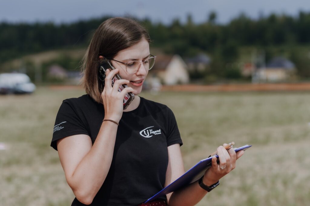 Frau telefoniert am Handy und prüft etwas auf einem Klemmbrett